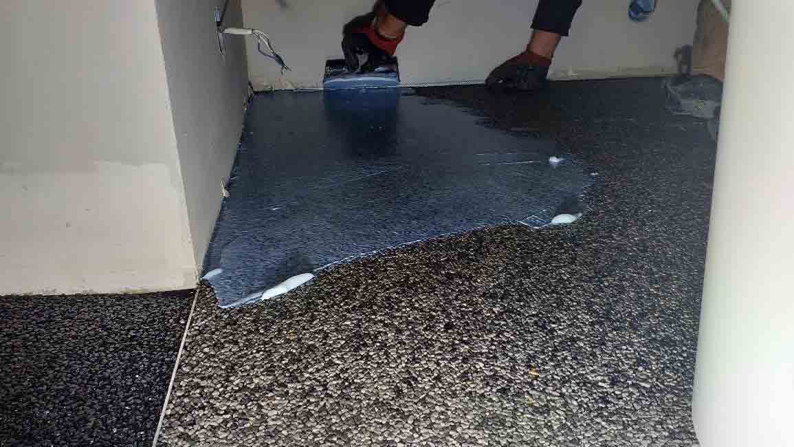 Application de résine lors de la pose d’un sol en moquette de pierre en intérieur