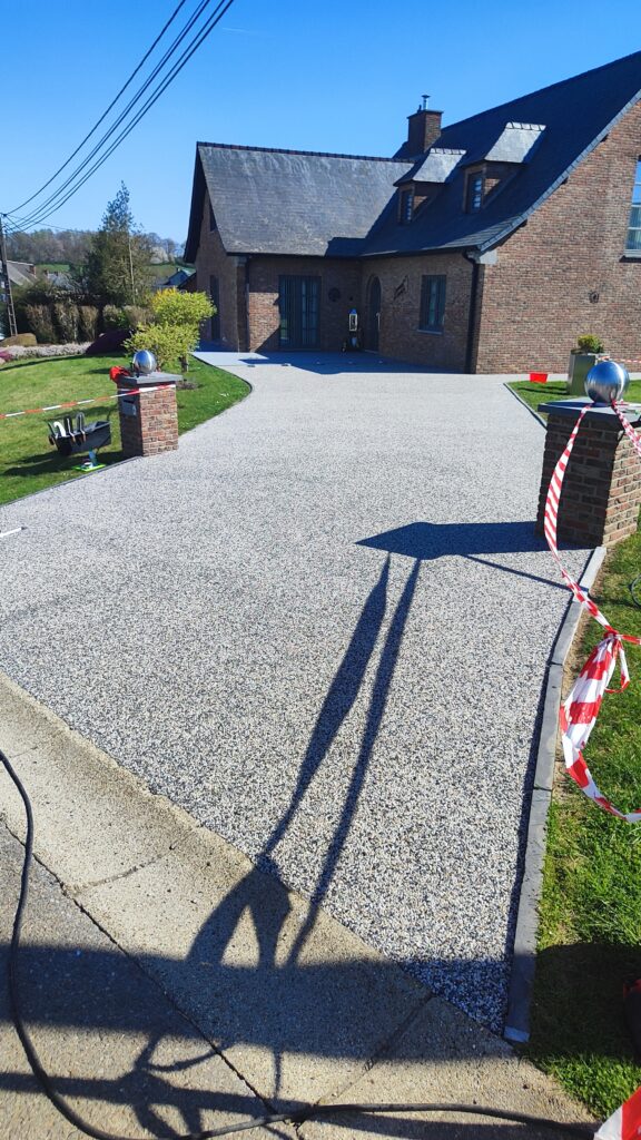 Maison en briques avec grande allée extérieure recouverte de moquette de pierre claire